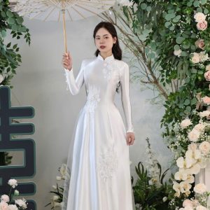 Cô dâu mặc áo dài trắng cầm ô đứng giữa không gian ngập tràn hoa trắng tinh khôi.