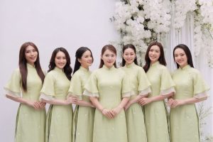 Nhóm phụ nữ mặc áo dài màu xanh pastel thanh lịch chụp tại studio với decor hoa trắng.