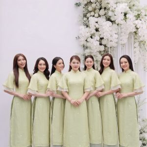 Nhóm phụ nữ mặc áo dài màu xanh pastel thanh lịch chụp tại studio với decor hoa trắng.