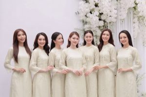Nhóm các cô gái mặc áo dài trắng ngà thanh lịch trong studio với decor hoa trắng.
