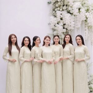 Nhóm các cô gái mặc áo dài trắng ngà thanh lịch trong studio với decor hoa trắng.
