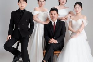 Ảnh chụp nhóm người mặc trang phục vest và váy trắng sang trọng trong studio.