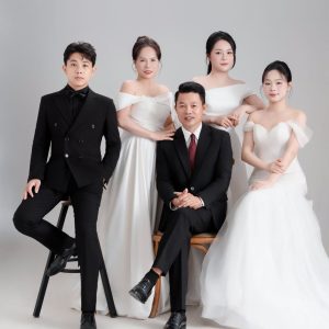 Ảnh chụp nhóm người mặc trang phục vest và váy trắng sang trọng trong studio.