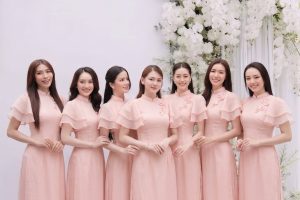 Nhóm các cô gái mặc áo dài hồng duyên dáng chụp tại studio với hoa trắng.
