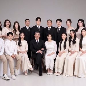 Ảnh chụp gia đình nhiều thế hệ với trang phục tông màu trắng và kem thanh lịch trong studio.