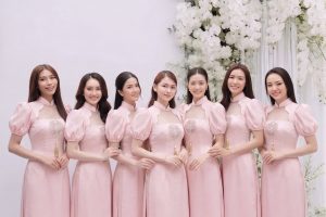 Một nhóm các cô gái mặc váy hồng pastel thanh lịch chụp tại studio với hoa trắng.