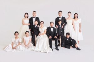 Ảnh chụp gia đình đông đủ thành viên với trang phục trắng và đen sang trọng trong studio.